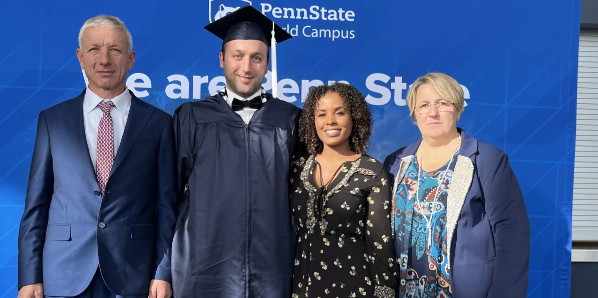 Male student in cap and gown with family
