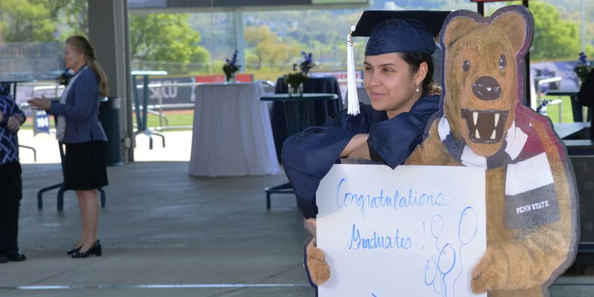 Graduate standing with cutout of Nittany Lion mascot