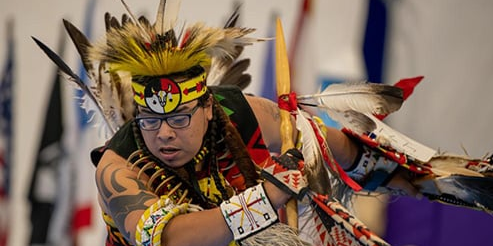 Native American male in traditional dress dancing