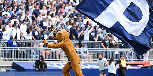 Nittany Lion mascot in Beaver Stadium with Flag