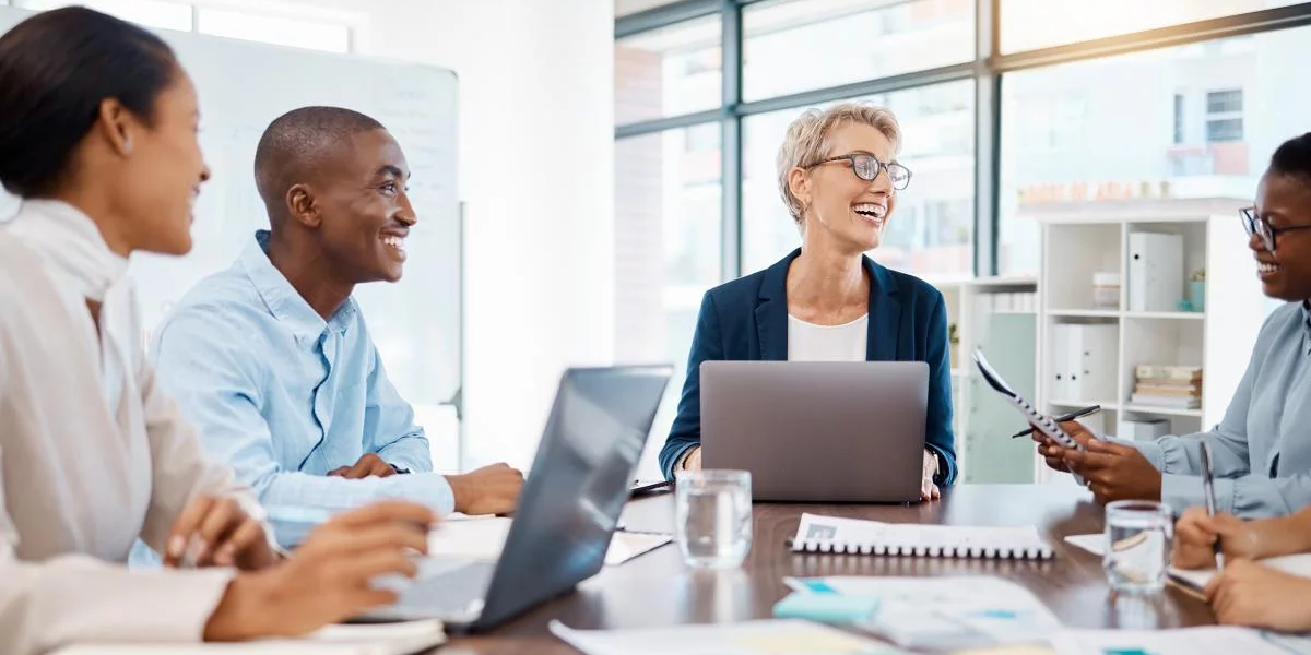 People with laptops laughing around a conference table