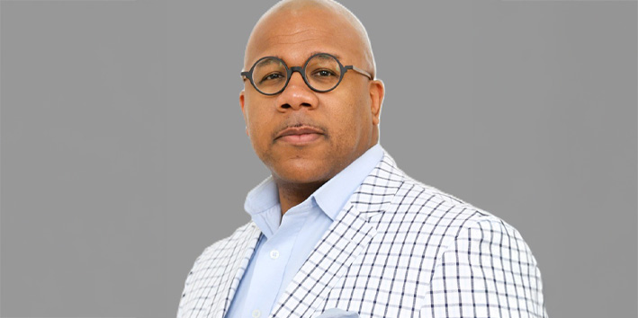 Randy Houston wears a white plaid suit coat and looks at the camera.