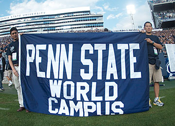 Two alumni holding the Penn State World Campus banner at Beaver Stadium