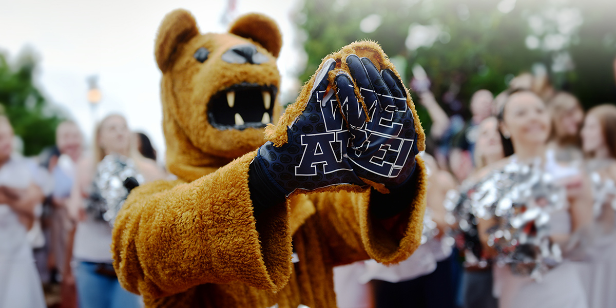 Penn State mascot holding his paws toward the camera. His gloves say, "We Are."