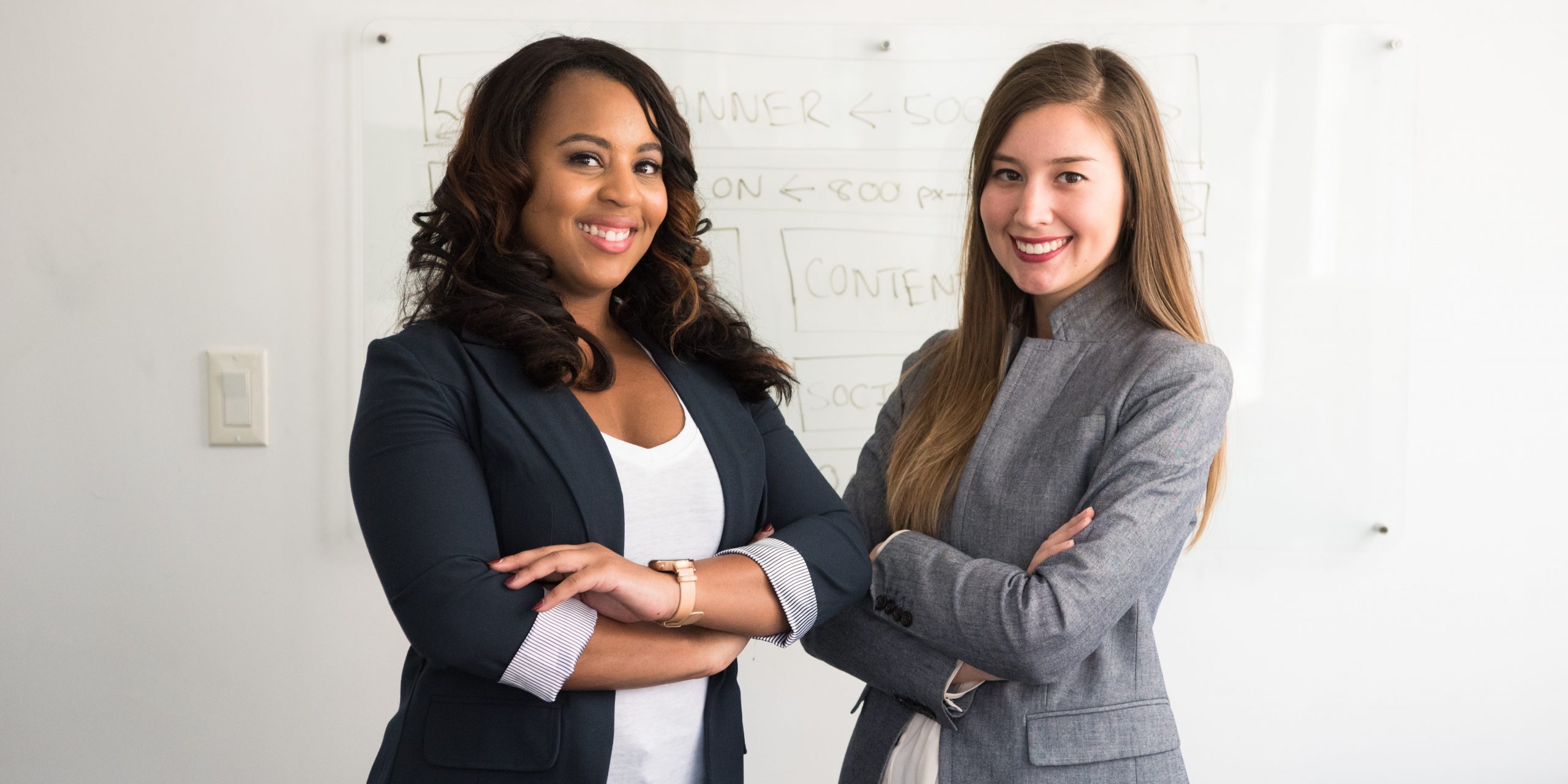 Two business women in front of white board